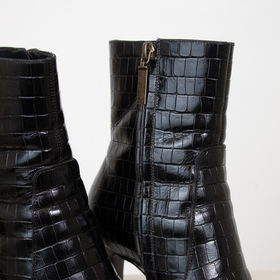 Black crocodile-embossed leather ankle boots with a side zipper and block heel, shown against a plain light background.