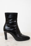 A single black ankle boot with a glossy crocodile-embossed texture and a high block heel, shown from a side profile against a white background.