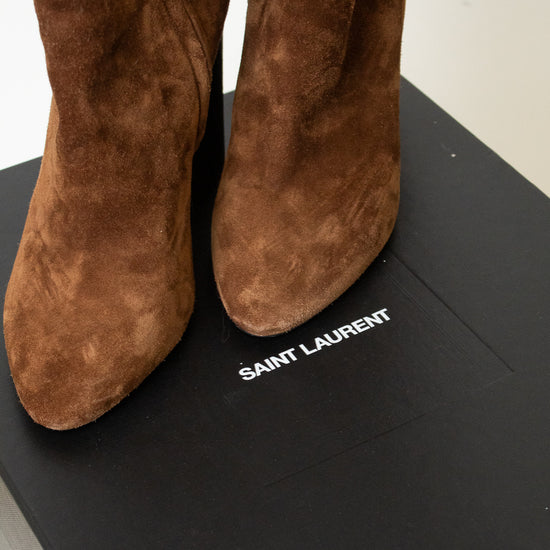 A pair of brown suede ankle boots shown sitting on a black "Saint Laurent" box