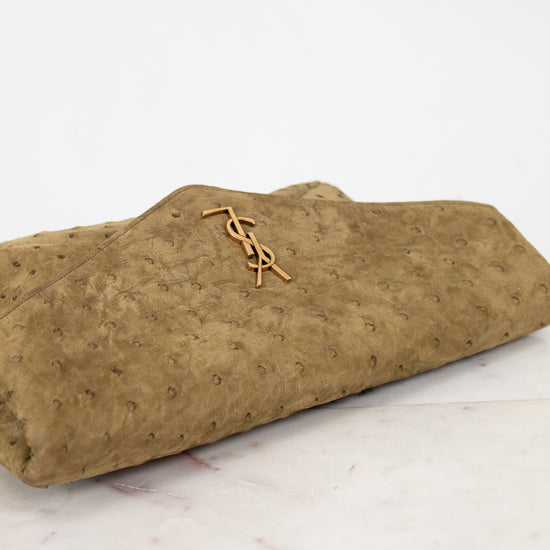 Brown textured clutch with gold YSL logo on a marble surface