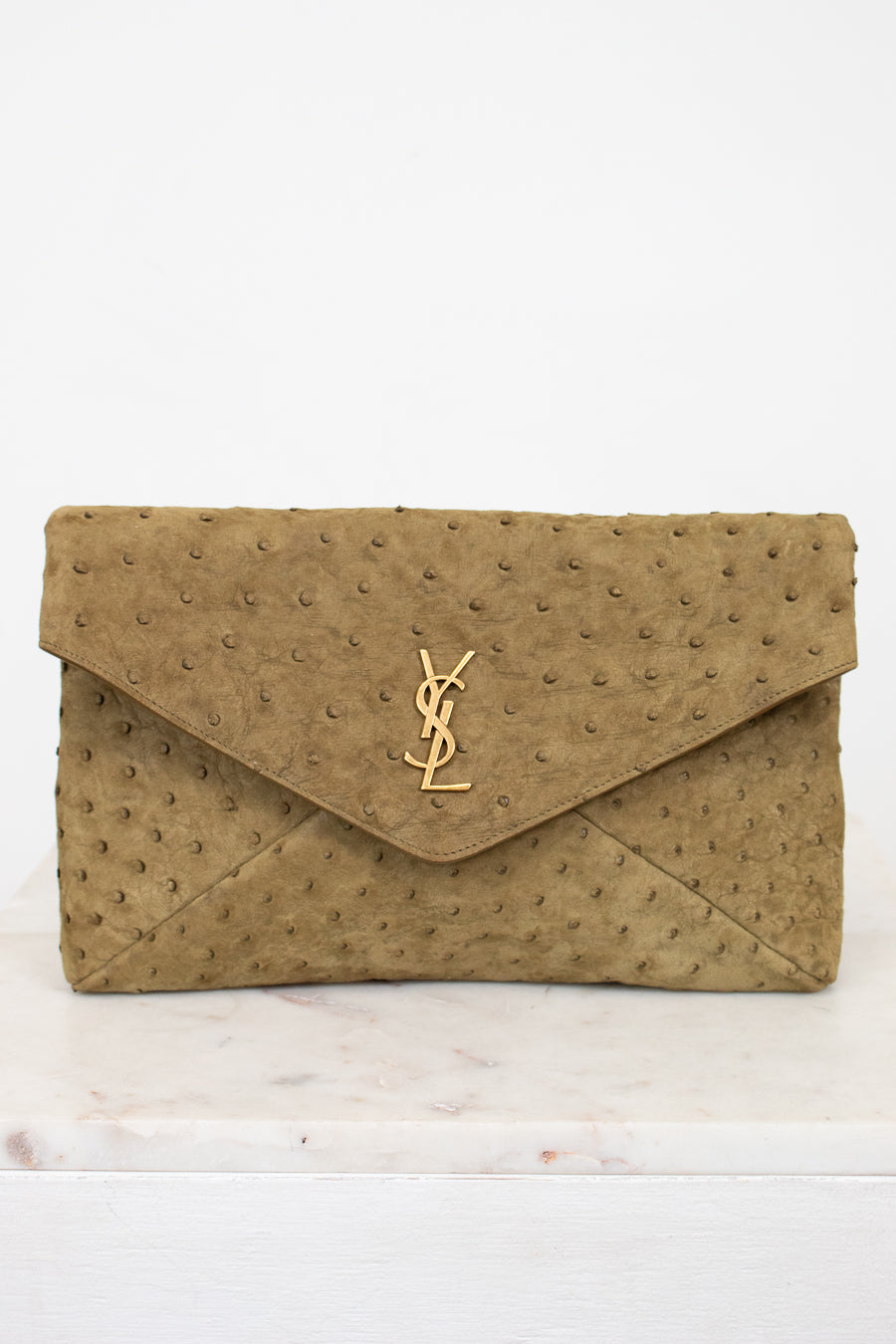 Beige clutch bag with a "YSL" brand logo on a white background