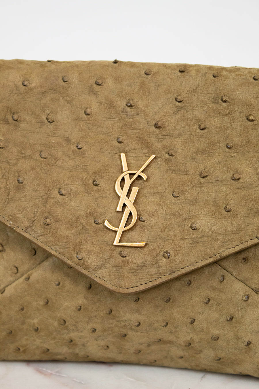 Beige handbag with a gold "YSL" logo on a light background