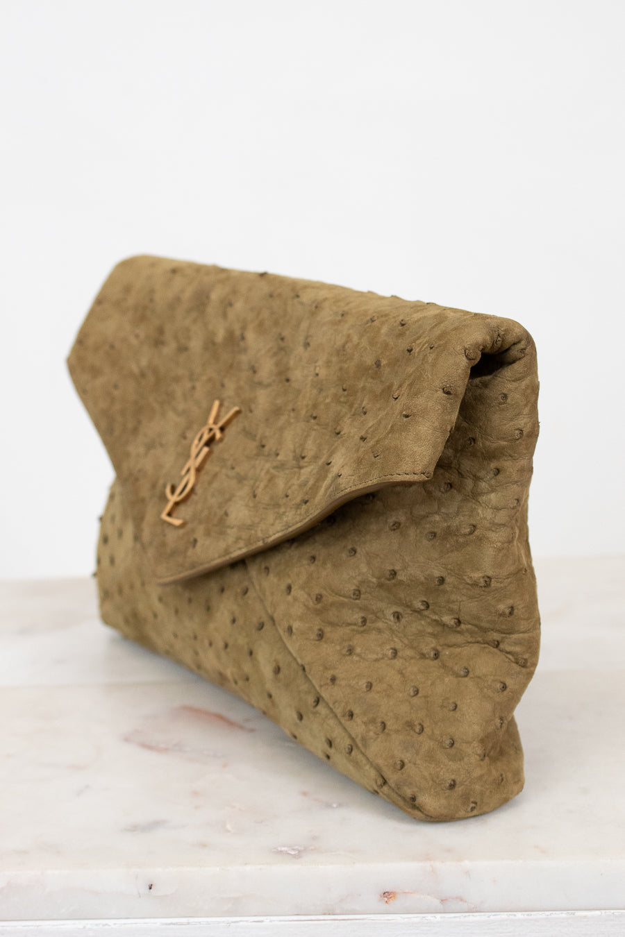 Brown clutch bag with a brand logo on a white surface