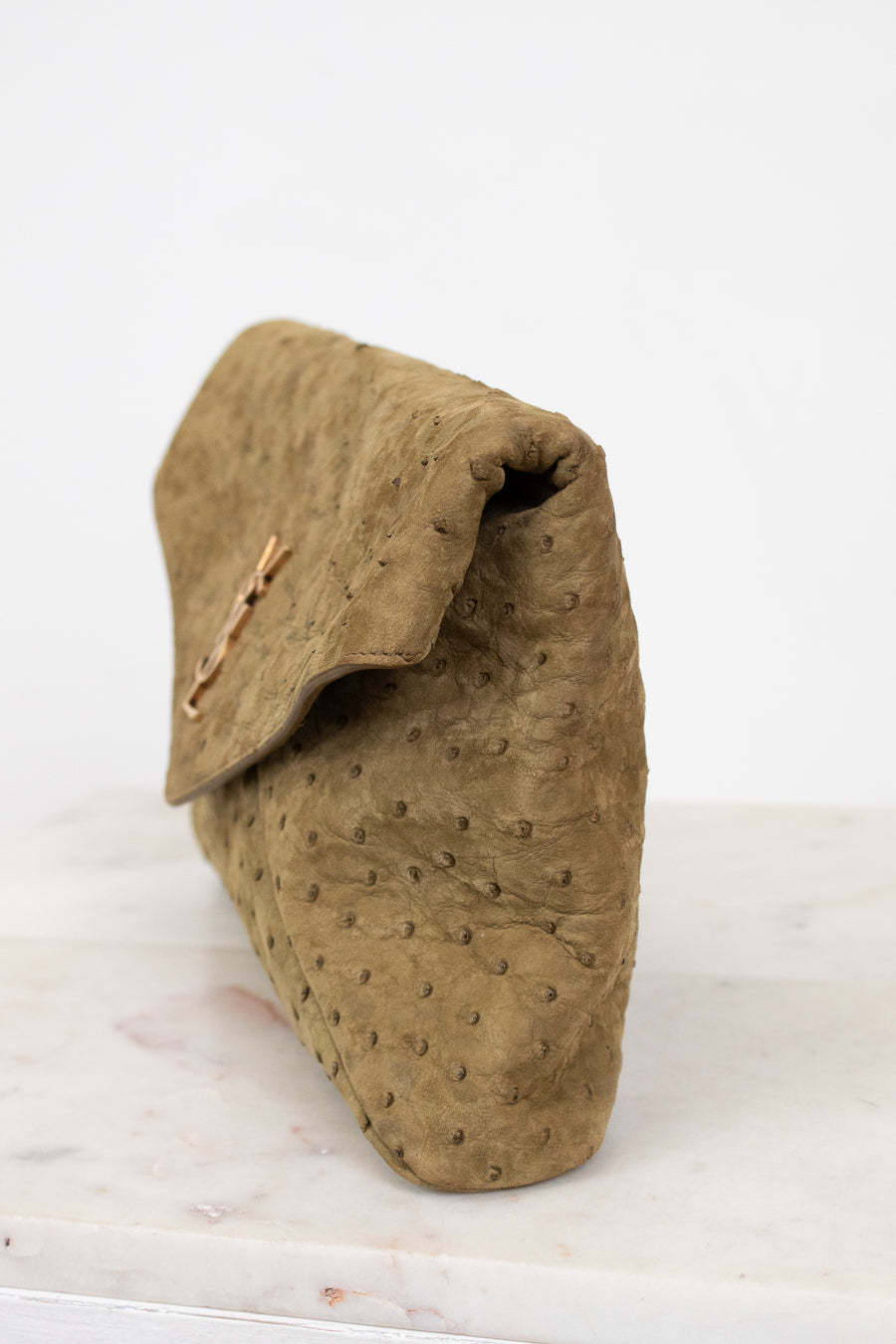Brown textured clutch bag on a white surface