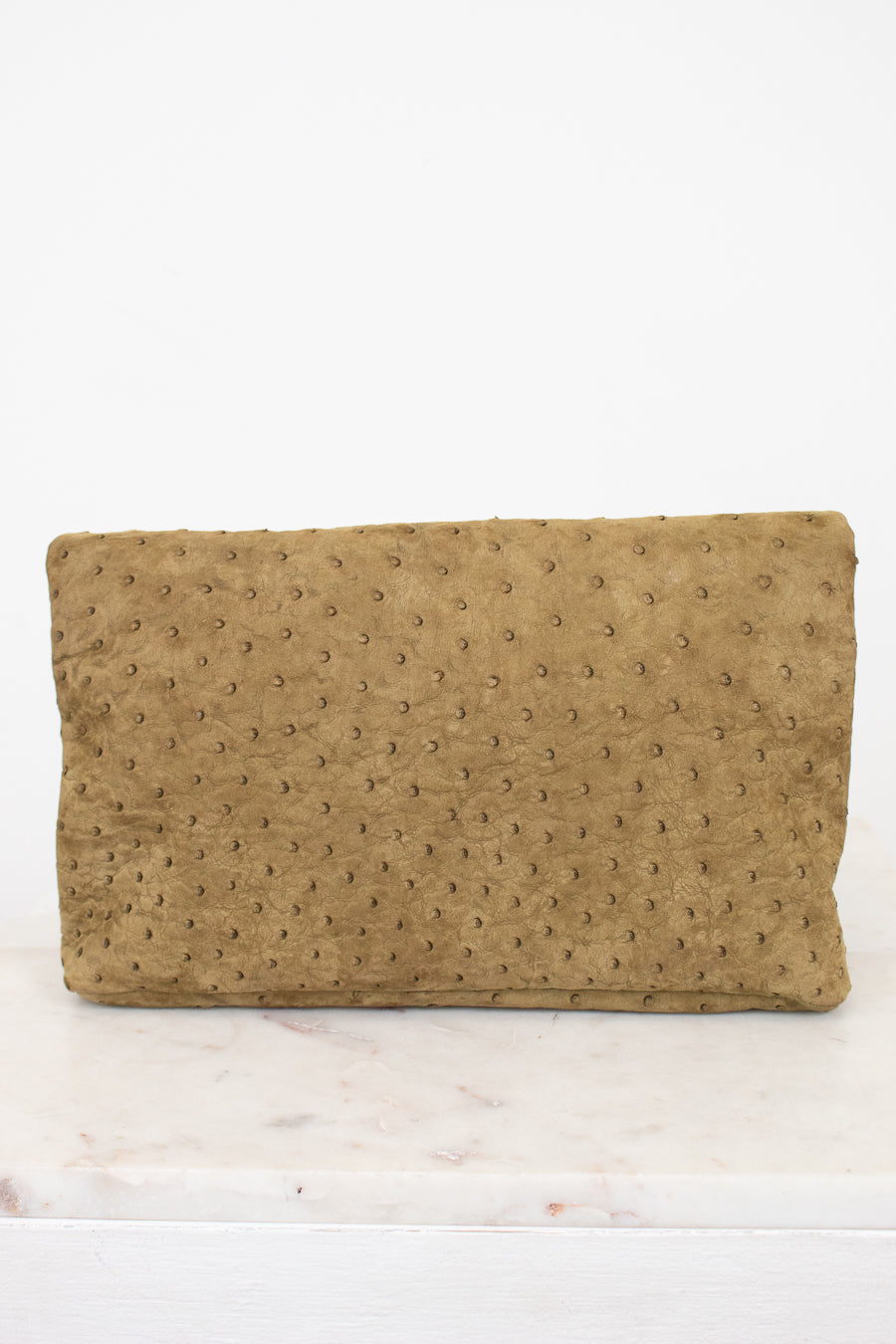 Brown textured clutch bag on a white marble surface