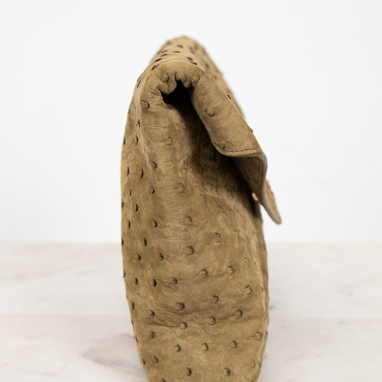 Beige clutch handbag with textured design on a white background