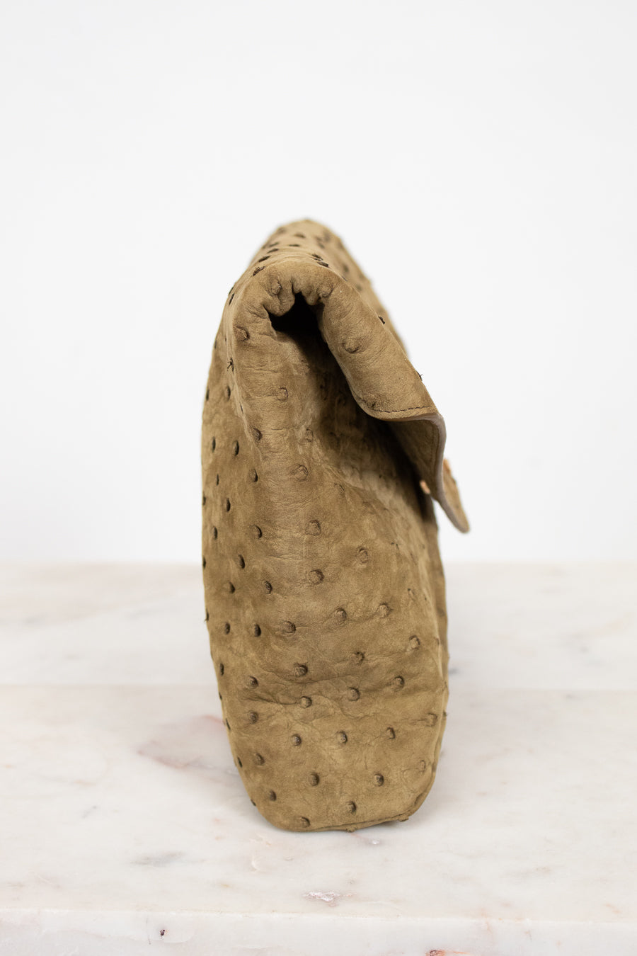 Beige clutch handbag with textured design on a white background