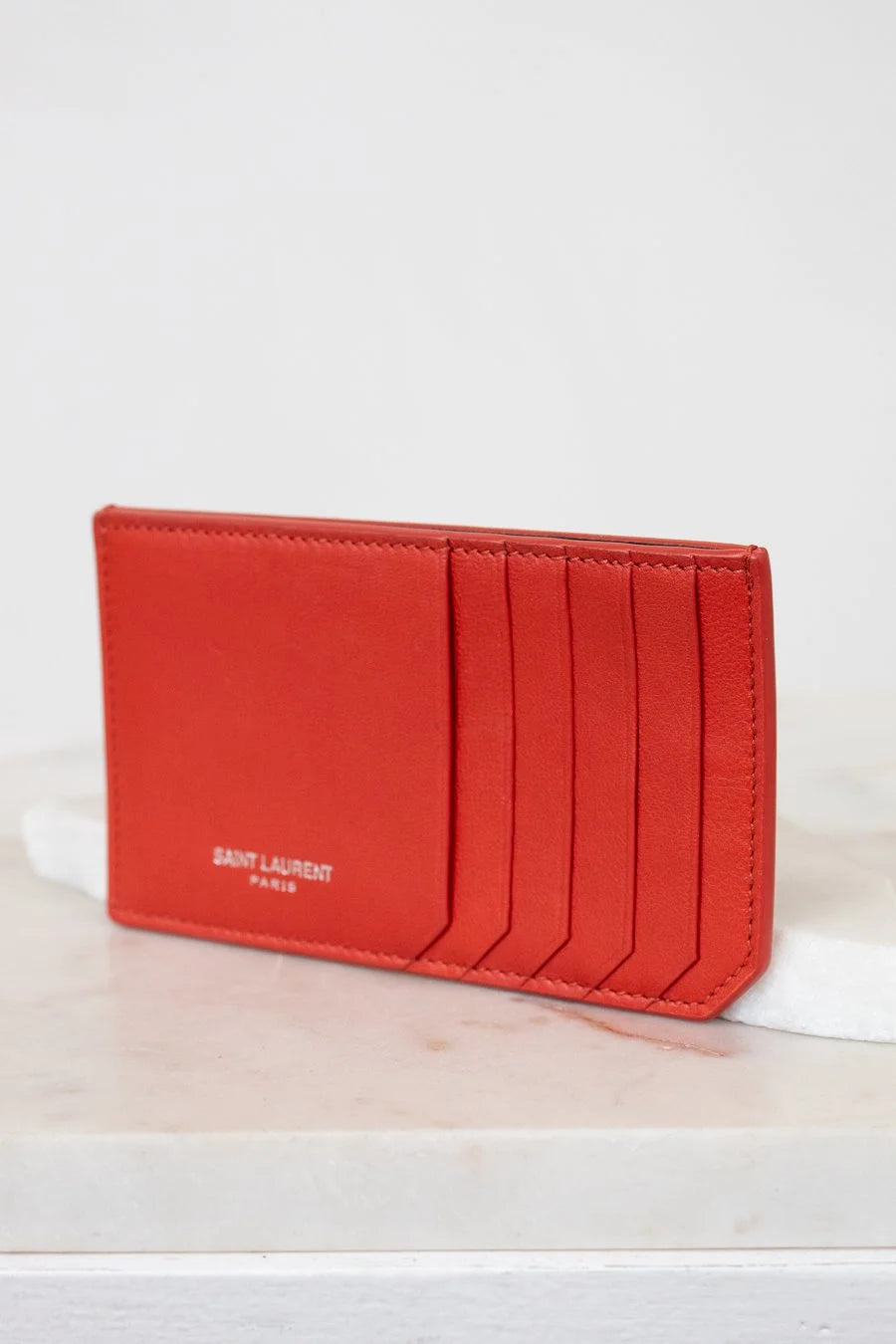 Red cardholder with Saint Laurent logo on a white surface