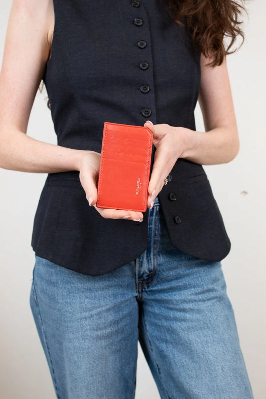 Person holding a red wallet with a plain background