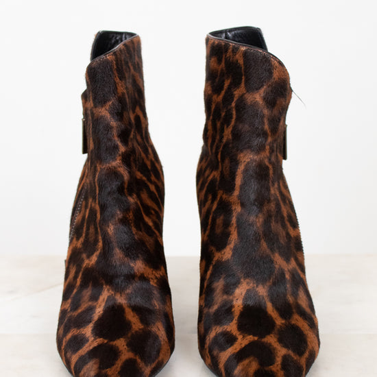 A pair of pointed-toe ankle boots with a brown and black leopard print pattern, photographed against a clean white background.