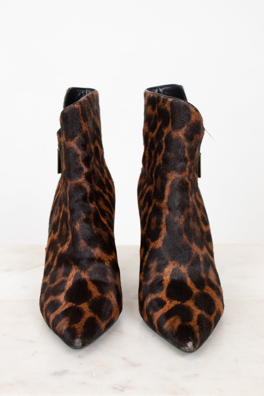 A pair of pointed-toe ankle boots with a brown and black leopard print pattern, photographed against a clean white background.