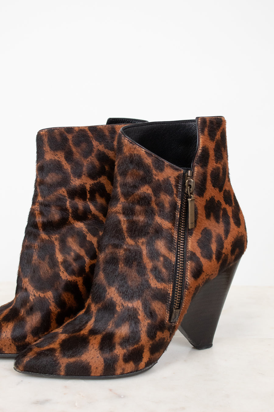 Side view of black and brown leopard print pointed toe ankle boot with conical heel.