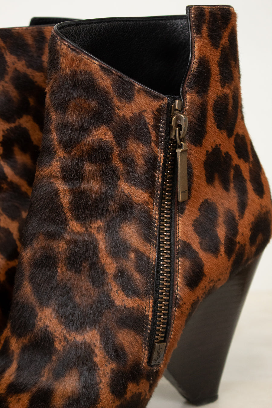 Close-up of a leopard-print ankle boot with a side zipper and block heel, shown against a plain light background.
