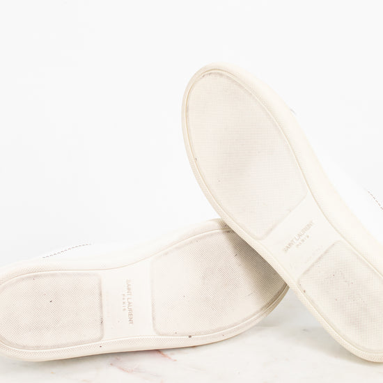 A pair of off-white leather shoes shown from the sole side, resting on a light marble surface against a white background.