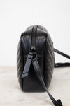 A black quilted leather shoulder bag shown from a side profile view, resting on a light marble surface against a white background.