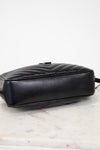 A black quilted leather handbag shown from a side angle, resting on a white marble surface against a white background.