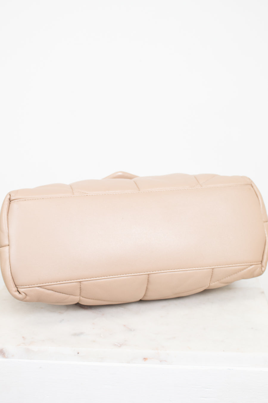 Beige quilted handbag on a white background