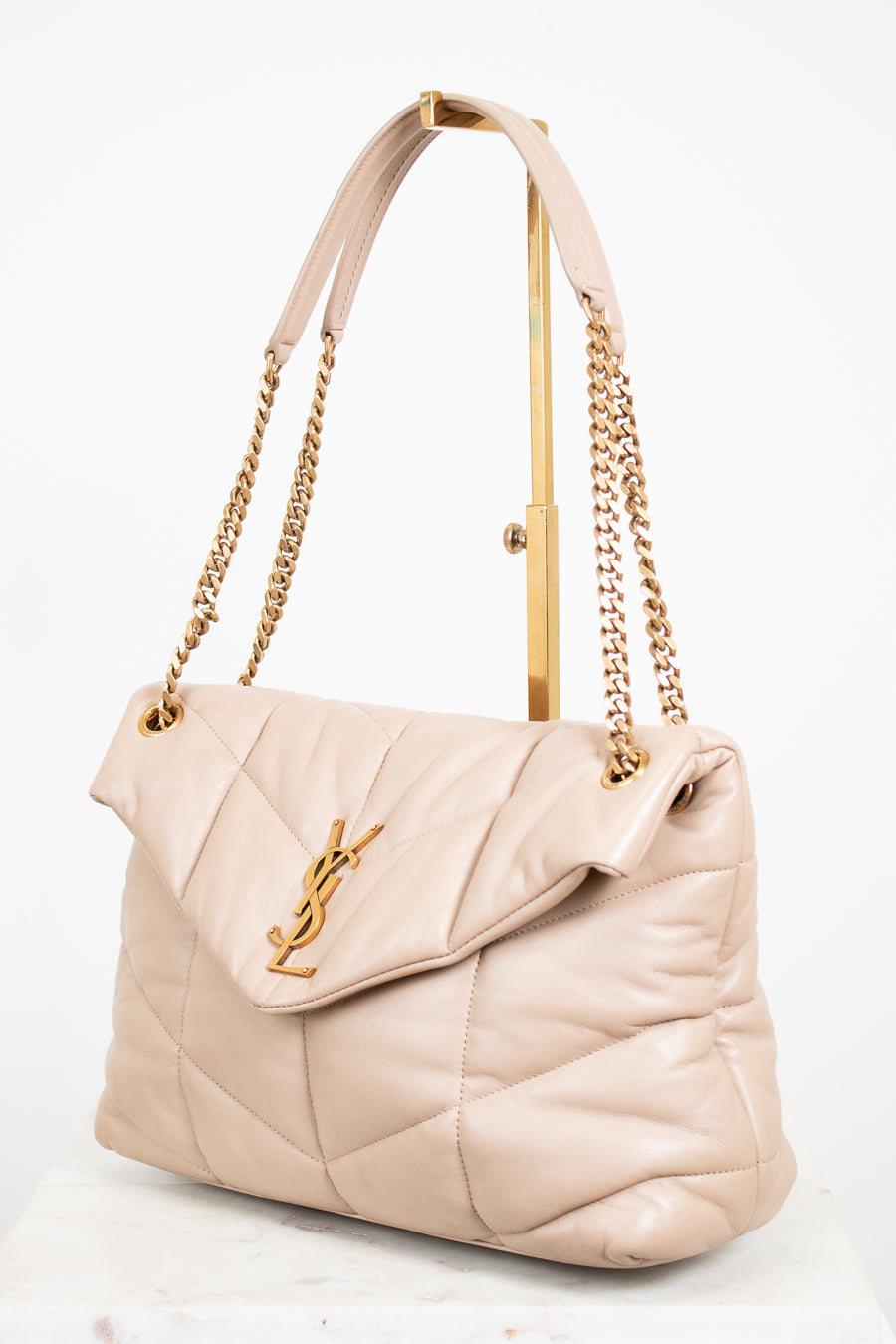 Beige handbag with gold chain and handle on a white background