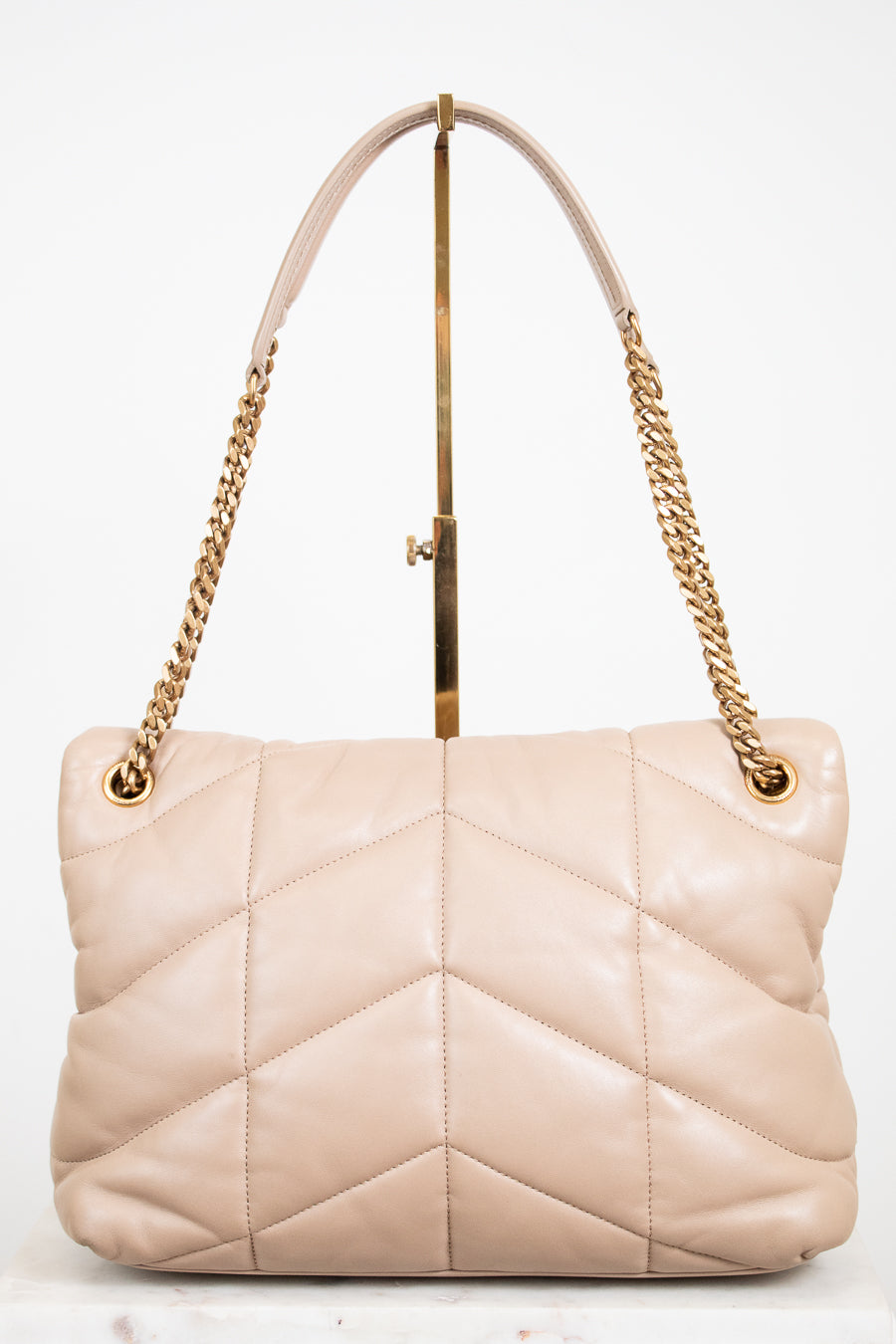 Beige quilted handbag with gold chain straps on a white background