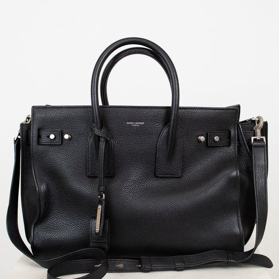 Black leather handbag with a shoulder strap on a white background