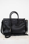 Black leather handbag with a shoulder strap on a white background