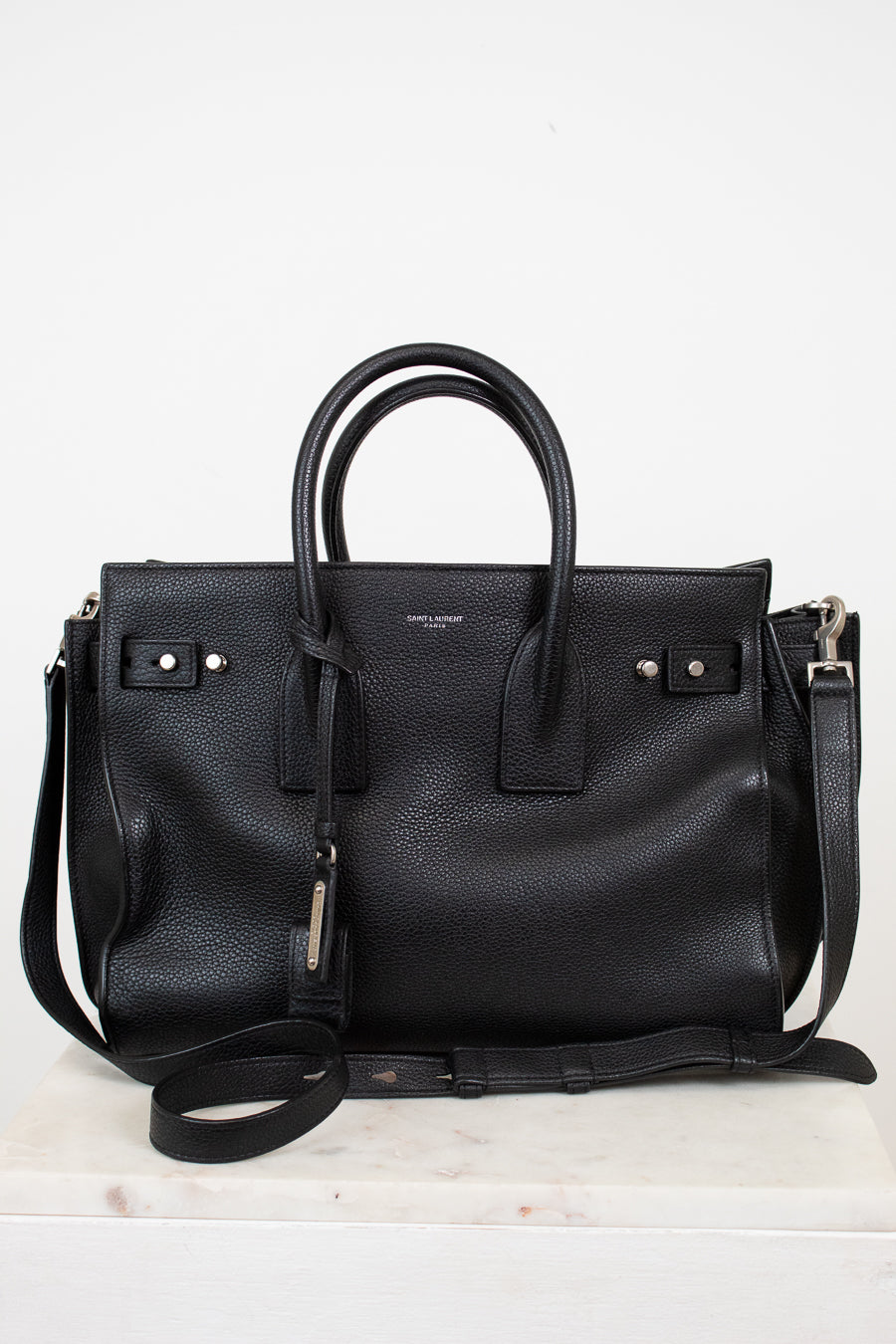 Black leather handbag with a shoulder strap on a white background