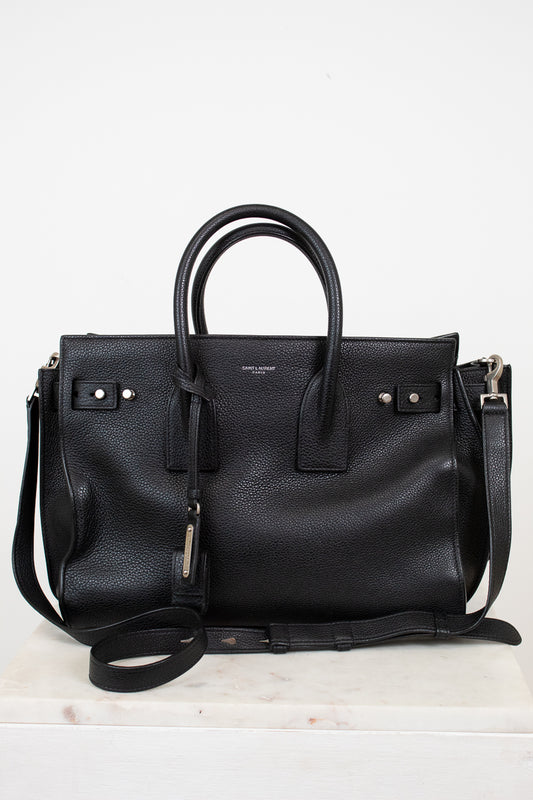 Black leather handbag with a shoulder strap on a white background