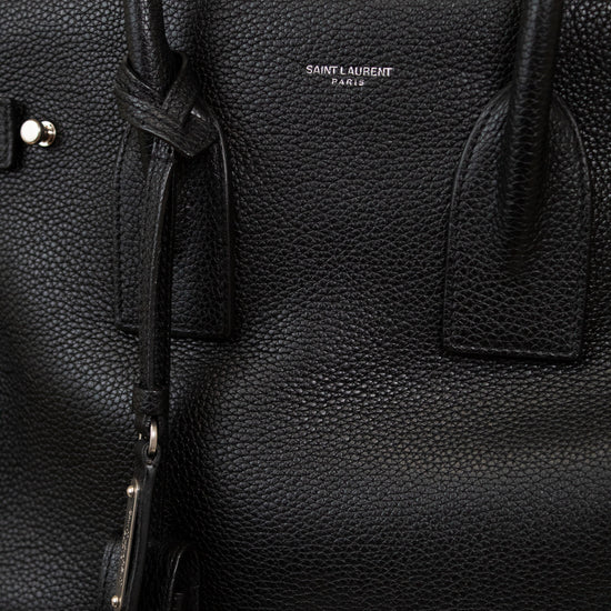 Black leather handbag with 'Saint Laurent' branding on a light gray background