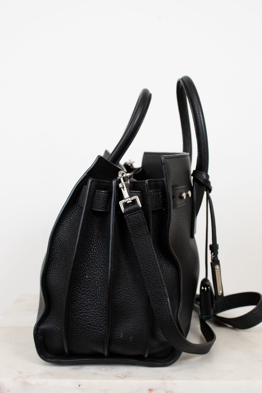 Black leather handbag on a light gray background