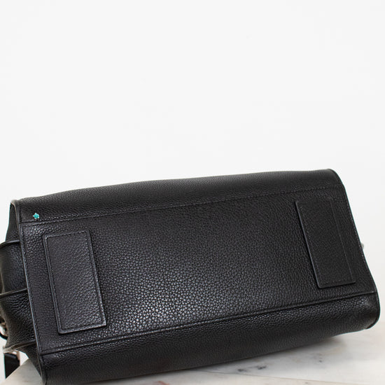 Black leather handbag on a light marble surface