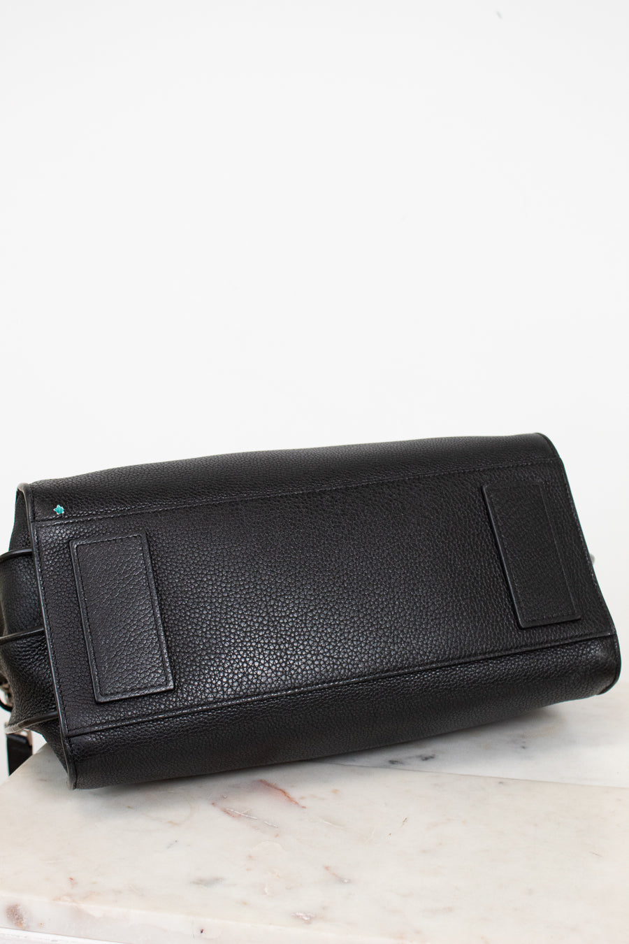 Black leather handbag on a light marble surface