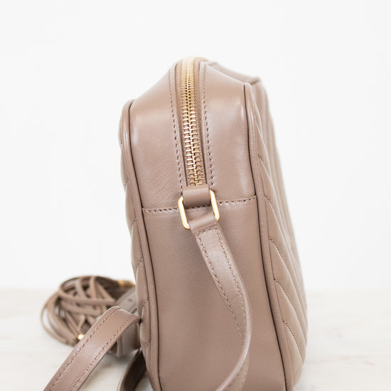 Beige quilted handbag with a gold zipper on a white background