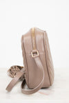 Beige quilted handbag with a gold zipper on a white background