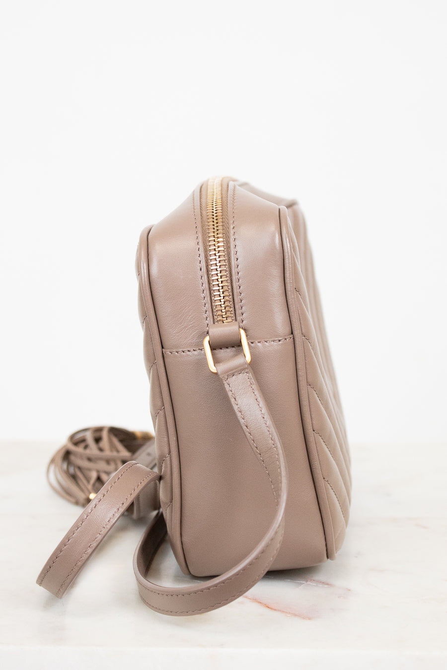 Beige quilted handbag with a gold zipper on a white background