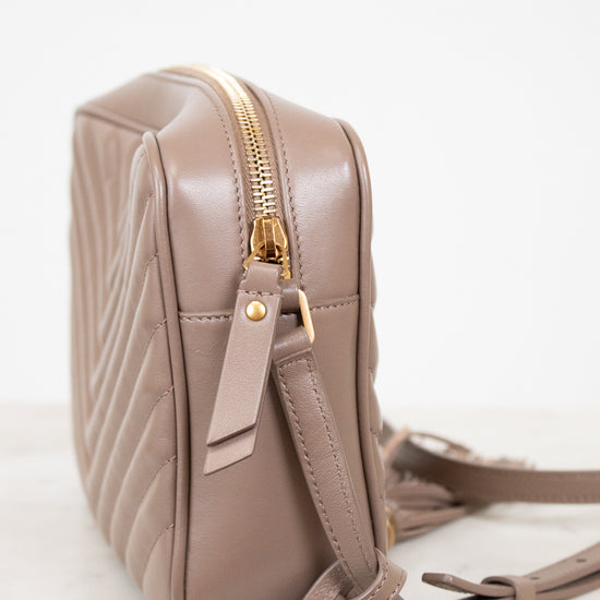 Beige quilted handbag with gold zipper on a light gray background