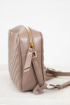 Beige quilted handbag with gold zipper on a light gray background