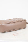 Taupe handbag with a gold clasp on a light pink background
