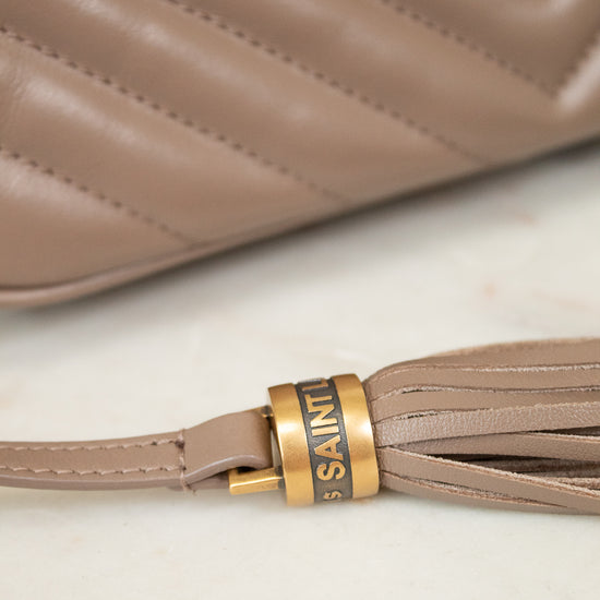 Close-up of a beige handbag with a tassel detail and 'Saint Laurent' branding.