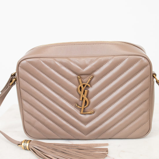 Beige handbag with tassel and brand logo on a white background