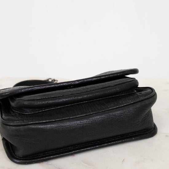 Black leather shoulder bag on a marble surface