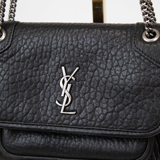 Black leather handbag with a chain strap on a light gray background