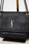Black leather handbag with a chain strap on a light gray background