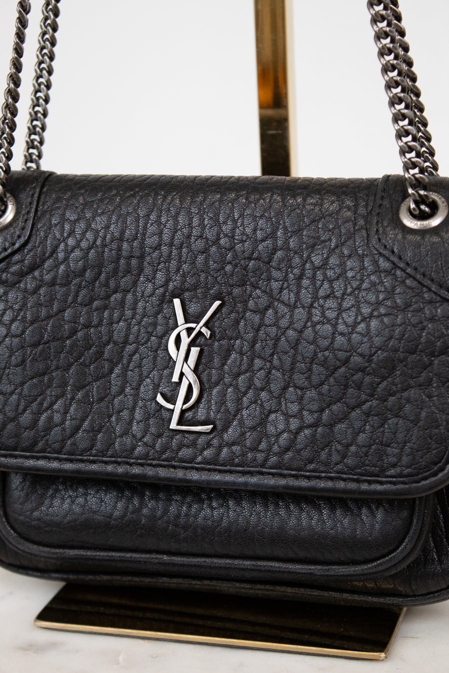 Black leather handbag with a chain strap on a light gray background