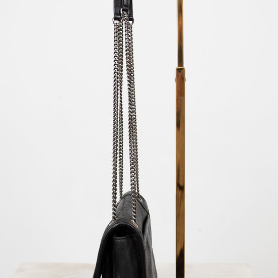 Black handbag with a chain detail on a gold stand against a white background