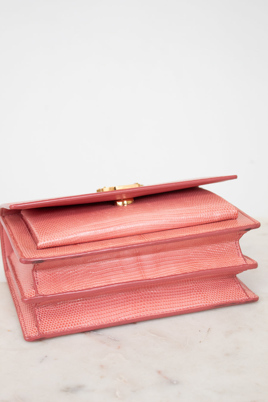 Bottom view of pink lizard leather bag with gold-tone hardware