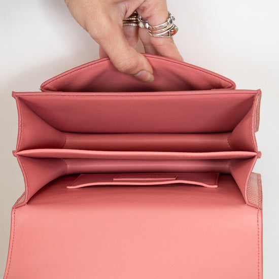 Pink interior of handbag held open by hands