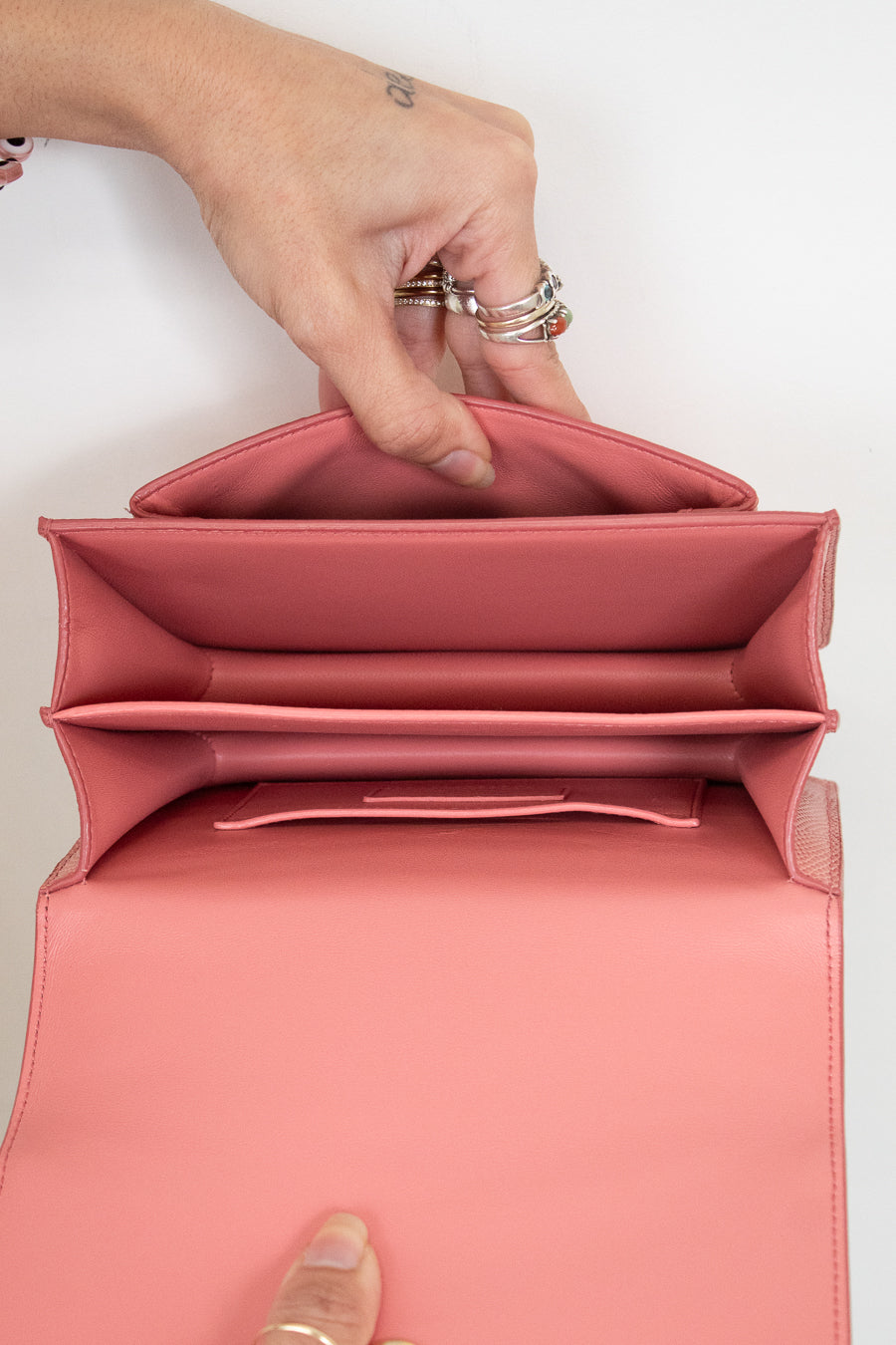 Pink interior of handbag held open by hands