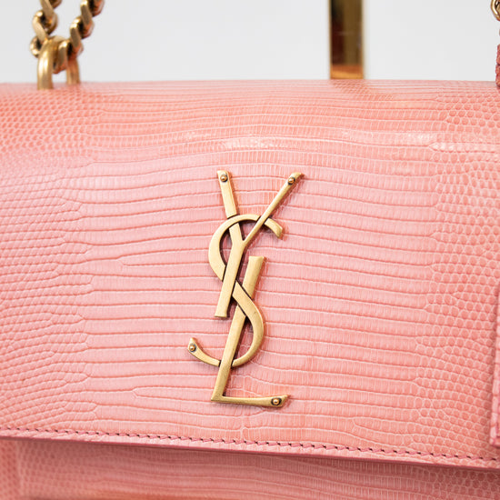 Close-up of gold 'YSL' logo against pink lizard leather