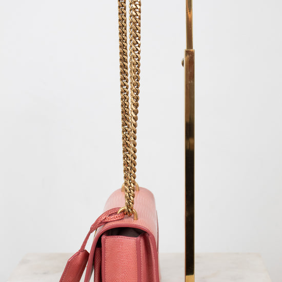 Side view of pink lizard bag with gold chain straps on gold stand