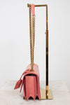 Side view of pink lizard bag with gold chain straps on gold stand
